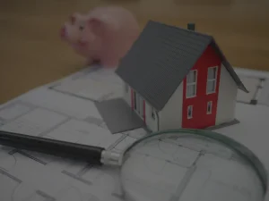 Model house and magnifying glass on paperwork